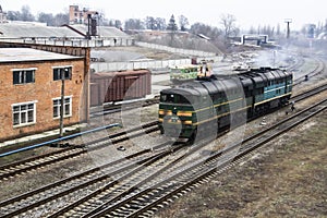 Ukrainian train arrives in the city. On the rails part of the train rides. Old green locomotive rides on the rails