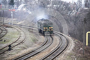 Ukrainian train arrives in the city. On the rails part of the train rides. Old green locomotive rides on the rails