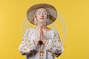 Ukrainian woman praying for Ukraine, victory, peace on yellow background. Girl begs God to save country, people