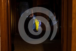 A Ukrainian woman stands near the door of an apartment with a suitcase and a flag of Ukraine and a passport in the dark without