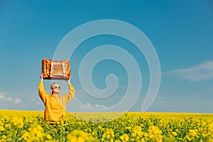 Ukrainian woman in yellow hoodie with bag in rapeseed field