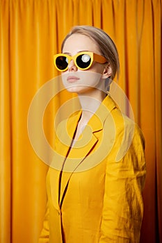 Ukrainian woman in yellow sunglasses and jacket on curtains background