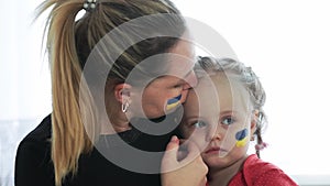 Ukrainian young mother with daughter with flag on the face with fear suffering and praying peace during war conflict