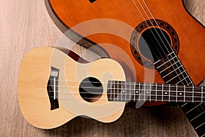 Ukulele and acoustic guitar on wooden background, flat lay. String musical instruments