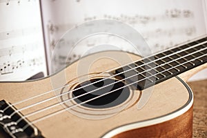 Ukulele chords. Close-up photo of ukulele guitar and music notes against of wooden background. Musical instruments