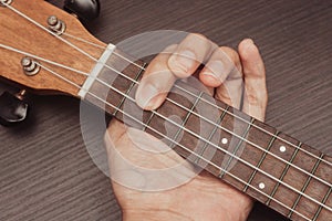 Ukulele in close up with hand placing chords. The chord is F. Portable string instrument. Music creation concept.  wooden