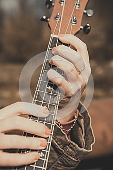 Ukulele - Closeup in the open air - Women`s hands - Instrument tuning