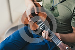 ukulele game. a man playing a little guitar. the performer writes the music on the ukulele at home
