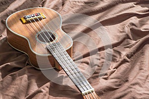 Ukulele guitar on bed background.