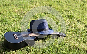 Ukulele with hat on green grass