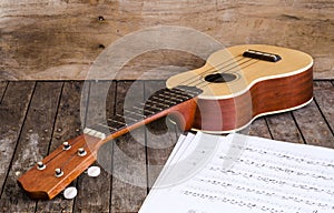 Ukulele and Paper Chordschart document on wooden background.