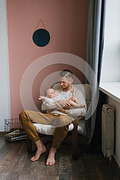 ul family a young dad holds a little son in his arms while sitting in an armchair