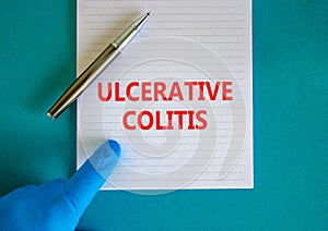 Ulcerative colitis symbol. White note with words Ulcerative colitis, beautiful blue background, doctor hand and metallic pen.