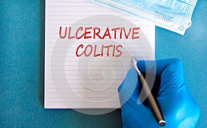 Ulcerative colitis symbol. White note with words Ulcerative colitis, beautiful blue background, doctor hand and metallic pen.