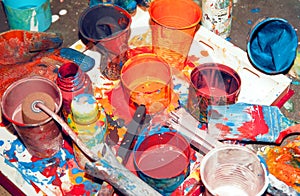 Ulticolored paints mixed in different jars and cups, painter`s tool