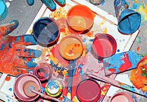 Ulticolored paints mixed in different jars and cups, painter`s tool