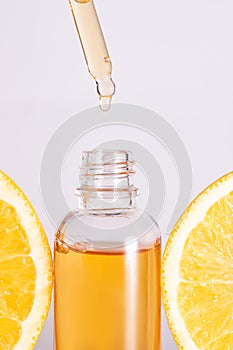 Ultra hydrating facial Vitamin C Serum Ad, Dropper bottle over sliced orange on white background. Skincare concept