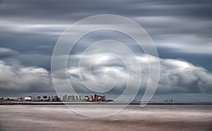 Ultra long exposure of skyscrappers near sea with clouds photo