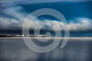 Ultra long exposure of skyscrappers and sea with clouds photo