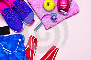 Ultra violet female sneakers, pink top blue sporting leggings and water bottle on pastel pink background flat lay top view with co