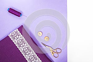 Sewing accessories on violet fabtic and white and light violet copy space