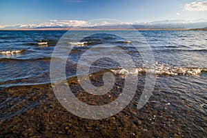 Ultra-wide angle view of small waves on mountain lake at sunny day. Low angle view.