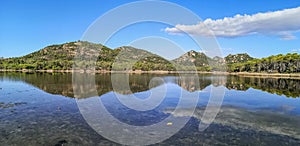 Ultra wide panorama of a mountains reflected in a lake in Sardinia