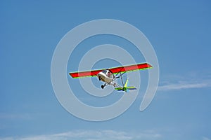 Ultralight plane flies  of blue sky and clouds