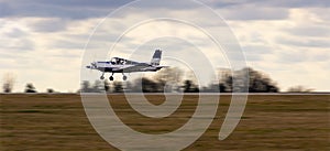 Ultralight plane take off from runway on airports with cloud sky. Panning photo