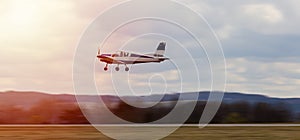 Ultralight plane take off from runway on airports with cloud sky and sun. Panning photo