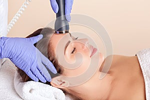 Ultrasonic cleaning procedure of the facial skin of a beautiful, young woman in a beauty salon.Cosmetology and professional skin