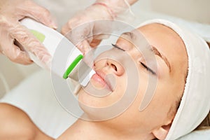 Ultrasonic skin equipment. Woman face cosmetology treatment. Female clinic