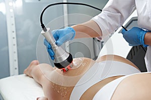 Ultrasound cavitation body contouring treatment. Woman getting anti-cellulite and anti-fat therapy in beauty salon