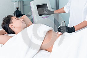 Ultrasound cavitation body contouring treatment. Woman getting anti-cellulite and anti-fat therapy on her leg in beauty