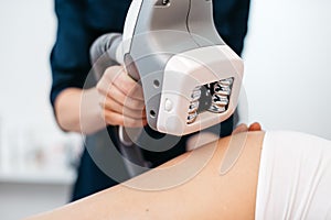 Ultrasound cavitation mashine in the hands of beautician. Close-up view. Woman is receiving the anti-cellulite treatment