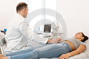 Ultrasound diagnosis of the pelvic organs of the girl. A girl lies on a couch in a white room of ultrasound diagnostics during a photo