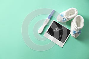 Ultrasound picture, baby shoes and pregnancy test on color background