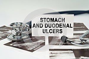 On the ultrasound pictures there is a stethoscope and a business card with the inscription - Stomach and duodenal ulcers