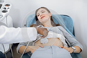 ultrasound scanner device in the hand of a professional African American doctor examining young Caucasian female patient
