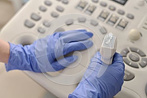 Ultrasound transducer with a gel in hand, looking at the doctor side at the panel