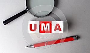 UMA word on wooden cubes with pen and magnifier photo