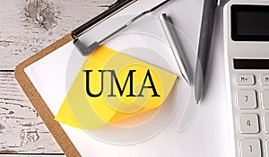 UMA word on a yellow sticky with calculator, pen and clipboard photo