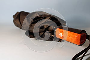Umbrella of black color with a plastic handle on a gray background.