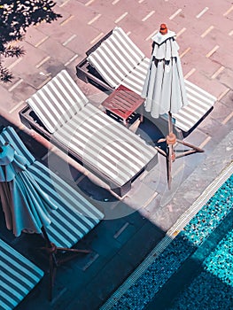 Umbrella and chair around luxury outdoor swimming pool