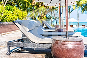 Umbrella and chair around swimming pool in hotel resort neary sea ocean beach for vacation