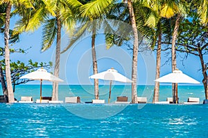 Umbrella and chair around swimming pool in hotel resort neary sea ocean beach for vacation