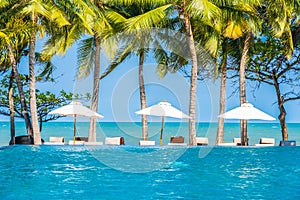 Umbrella and chair around swimming pool in hotel resort neary sea ocean beach for vacation