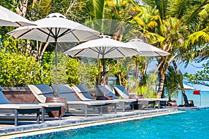 Umbrella and chair around swimming pool in hotel resort neary sea ocean beach for vacation