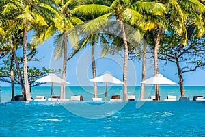 Umbrella and chair around swimming pool in hotel resort neary sea ocean beach for vacation