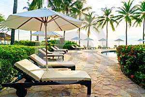 Umbrella and chair around swimming pool in resort hotel for leisure travel and vacation neary sea ocean beach